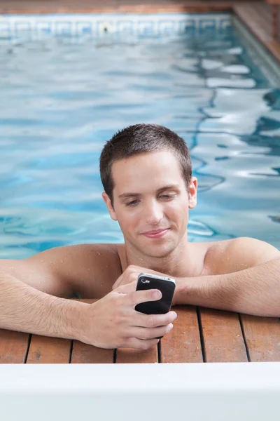 Чоловік грає з мобільним телефоном у басейні — стокове фото