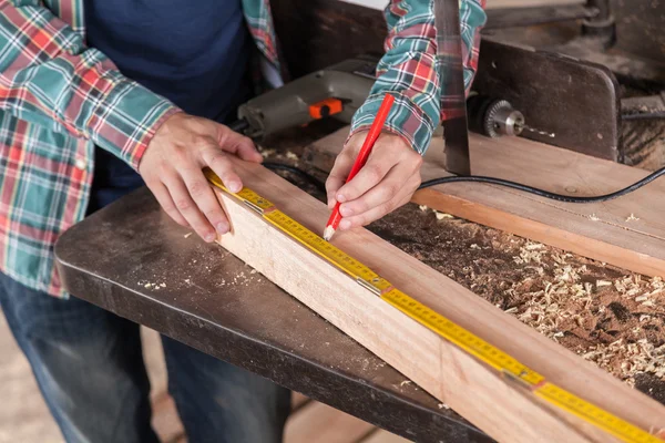 Carpintero midiendo un trozo de madera — Foto de Stock