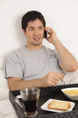 Kahvaltı yaparken telefonla konuşan adam