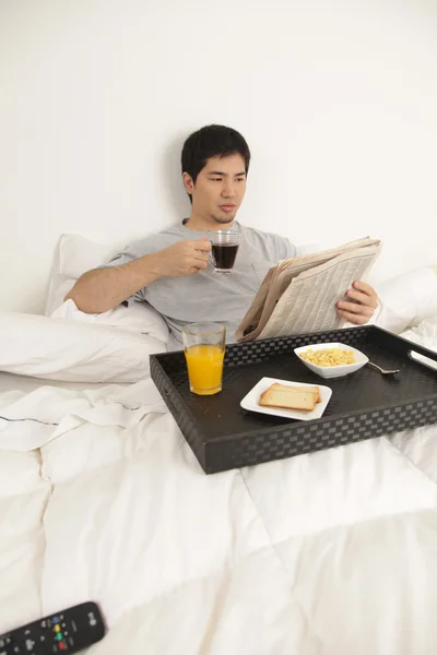 Человек завтракает, читая газету — стоковое фото