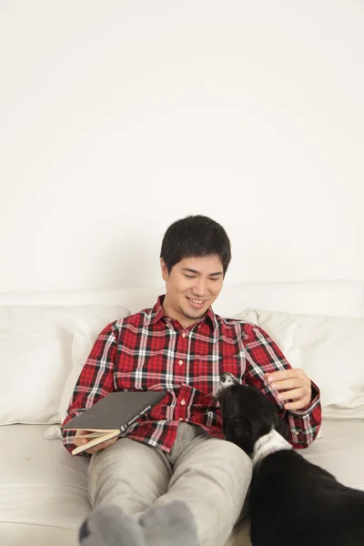 Man reading a book and  petting a dog — Stock Photo, Image