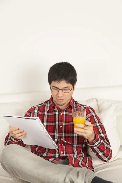 Hombre leyendo y bebiendo un jugo — Foto de Stock