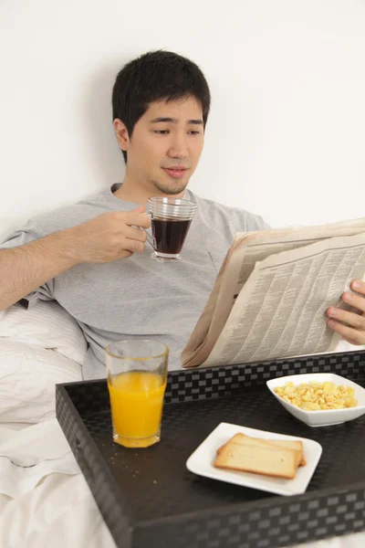 Hombre desayunando mientras lee el periódico — Foto de Stock