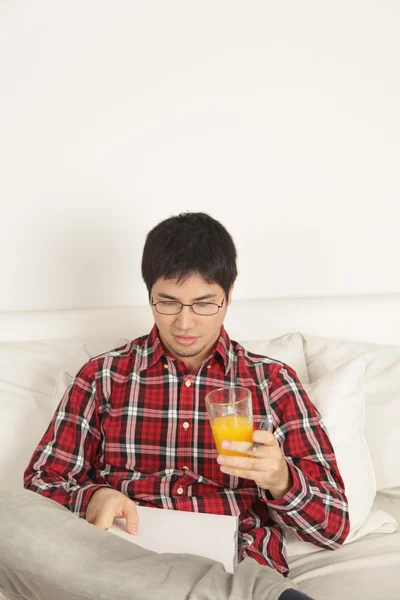 Hombre leyendo y bebiendo un jugo — Foto de Stock