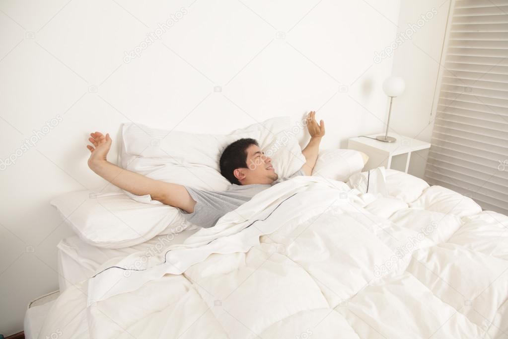 Man stretching in his bed