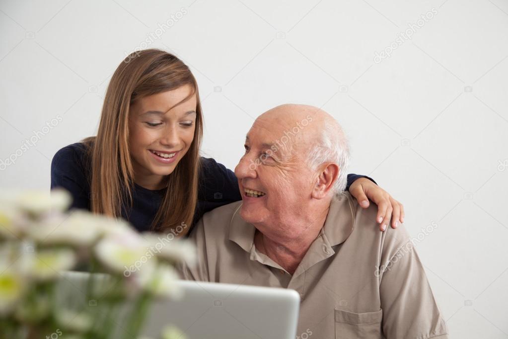 Girl helping to her grandfather with the computer