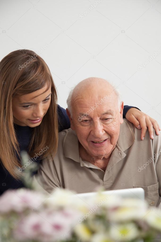 Girl helping to her grandfather with the computer