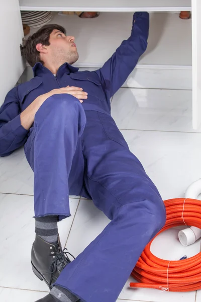 Encanador trabalhando deitado no chão — Fotografia de Stock