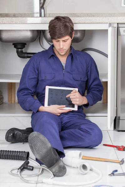 Plumber with a ipad sitting on the floor — Stock Photo, Image