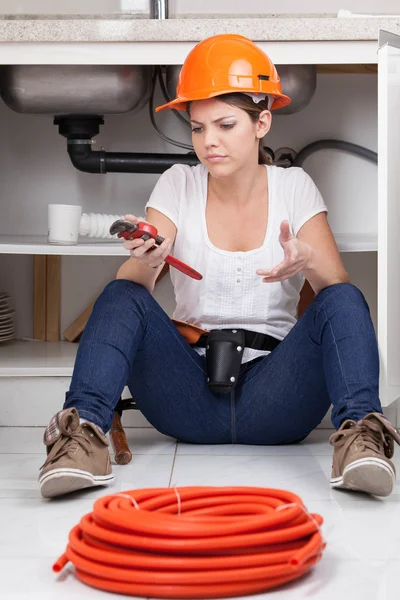 Confused woman plumber holding a wrench — Stock Photo, Image