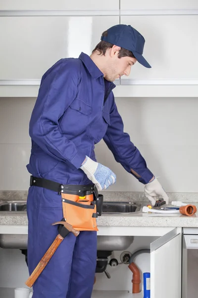 Plumber with tools in the kitchen — Stock Photo, Image