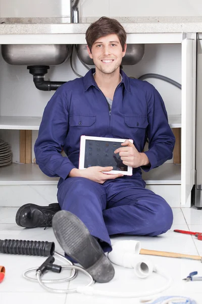 Plumber sitting on the floor with tablet — Stock Photo, Image