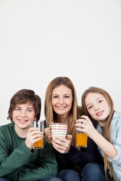 Mamma con figlio e figlia bere succo — Foto Stock