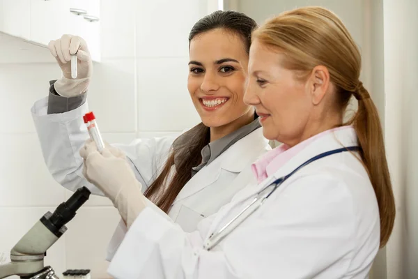 Casal em um laboratório olhando para os tubos — Fotografia de Stock