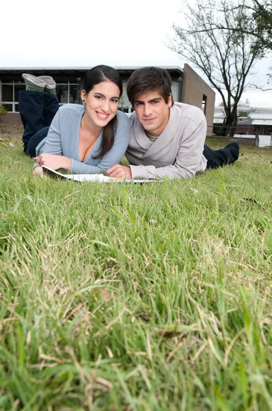 Coppia sdraiata sull'erba a studiare — Foto Stock