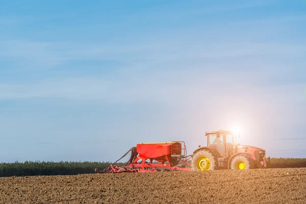 Sunset above the tractor harrowing the field — Stock Photo, Image