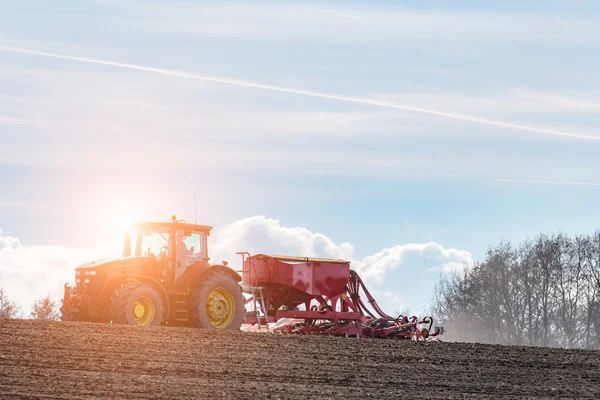 Sunset above the tractor harrowing the field — Stock Photo, Image