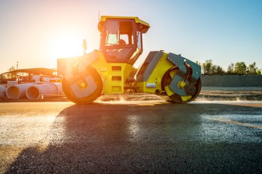 Günbatımı inşaat sitesinde çalışan yol silindiri yukarıda
