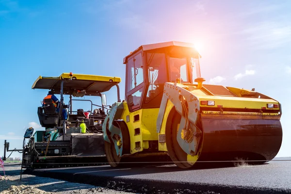 Puesta de sol sobre el rodillo de carretera trabajando en el sitio de construcción — Foto de Stock