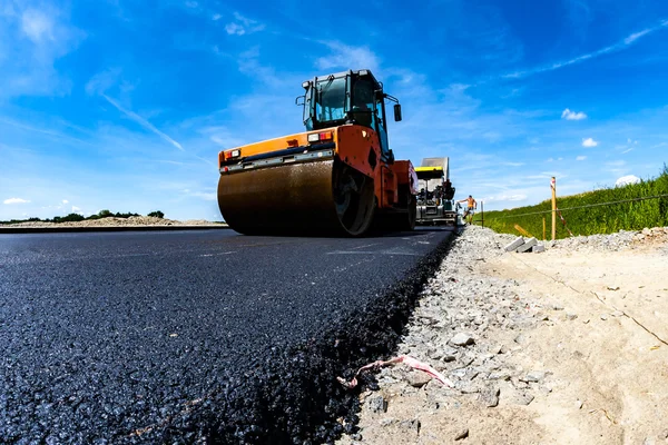 Rodillo de carretera trabajando en el sitio de construcción — Foto de Stock