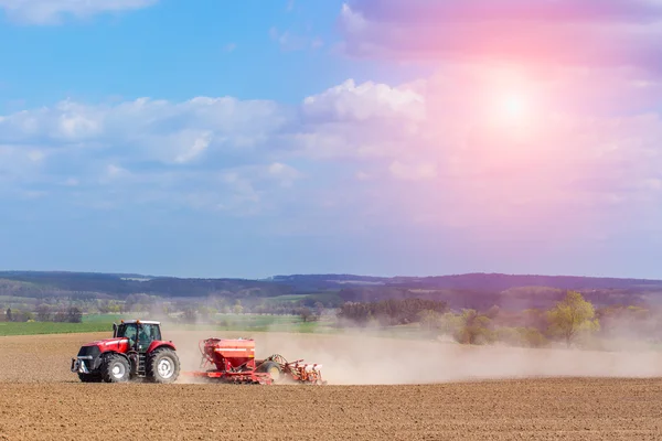 Naplemente a traktor szívszaggató a mező felett — Stock Fotó