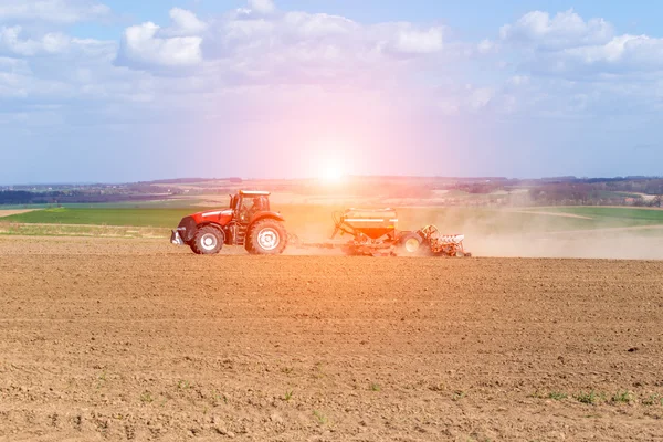 Sonnenuntergang über dem Traktor, der das Feld eggt — Stockfoto