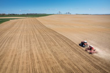 Aerial view of the tractor harrowing the field clipart