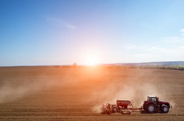 Vue aérienne du coucher du soleil au-dessus du tracteur qui herse le champ — Photo