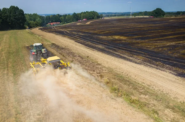 Tractor harrowing the field in fire — Stock Photo, Image