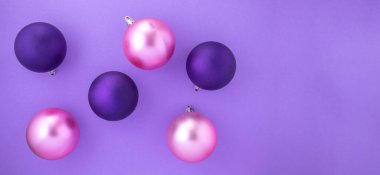 Noel süslemesi için mor arka planda mor ve pembe Noel topları ve metin için yer.