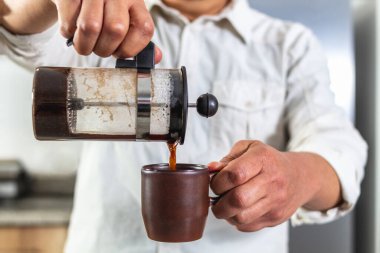 Fransız makinesinden kahve fincanına kahve servisi yapan bir adamın elleri. Seçici odak