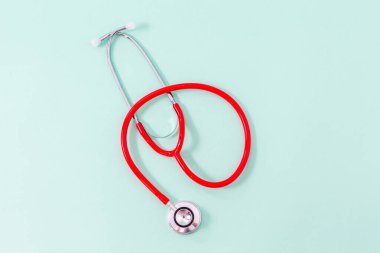 Aquamarine yeşil arka planda kırmızı steteskopun üst görüntüsü. Tıbbi nesneler