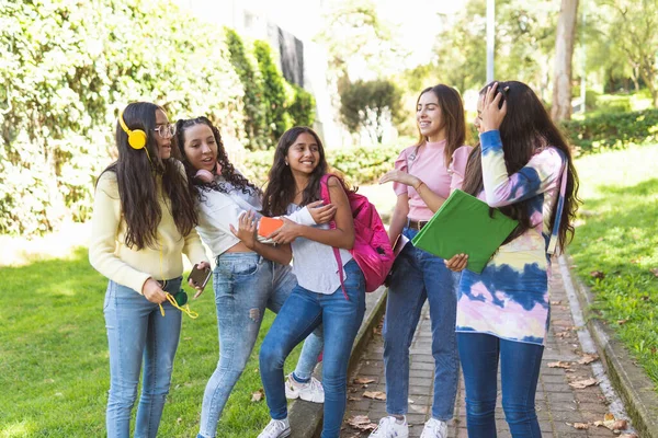 Group of five Latina teenage students laughing happily on the way to high school
