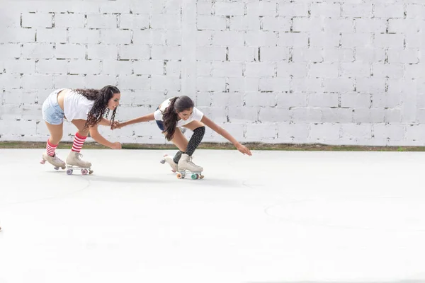 ショートパンツ 白いTシャツ 長い靴下の2人の友人は 白いブロックの壁の前で夏の朝にローラースケートでスケートを楽しみます — ストック写真