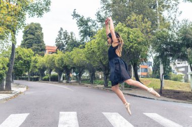 Dansçı kollarıyla caddede yaya geçidinin üzerinden atlıyor.