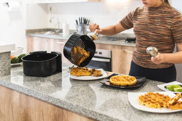 Kızarmış tavuk ve waffle servisi yapan bir kadın.