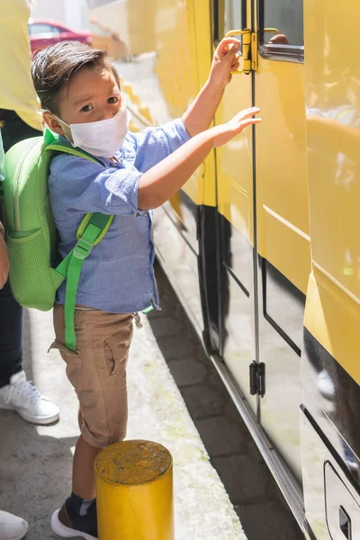 preschool boy getting on the school bus