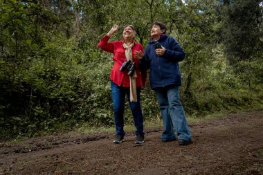 Aktif kıdemli kadınlar birlikte kuş gözlüyor, yürüyüş yapıyor, dışarıda eğleniyorlar.