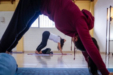 Anne ve küçük çocuk stüdyoda minderlerde yoga yapıyorlar.