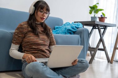 Kadın oturma odasında yerde otururken işine odaklanıyor.