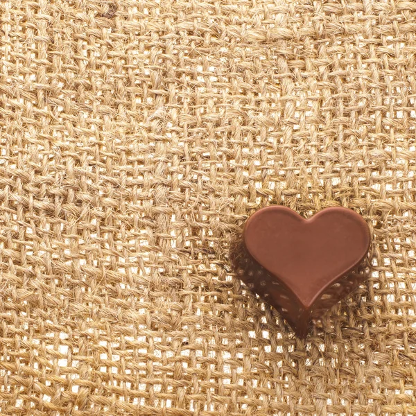 Coração de chocolate no fundo saco de tecido — Fotografia de Stock