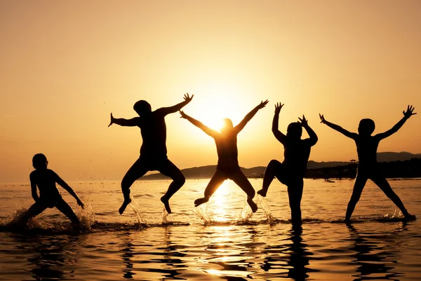 Silhouet van kinderen springen op het strand — Stockfoto