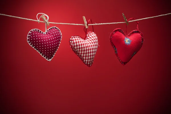 Colorful fabric hearts on red backgrounds — Stock Photo, Image