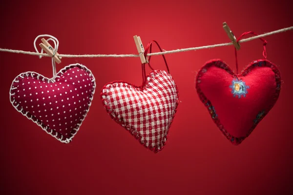 Colorful fabric hearts on red backgrounds — Stock Photo, Image