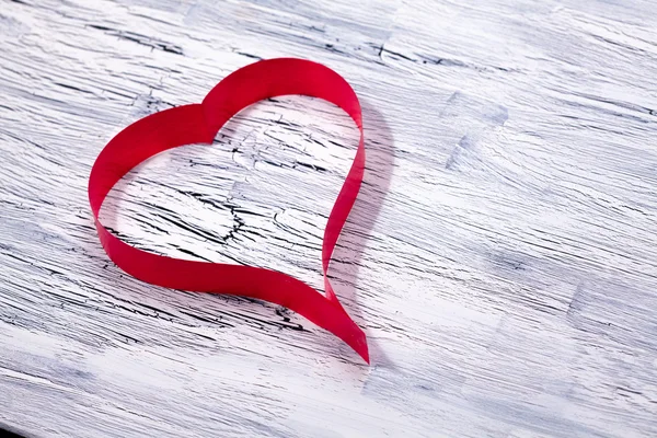 Red ribbon heart on wooden background — Stock Photo, Image