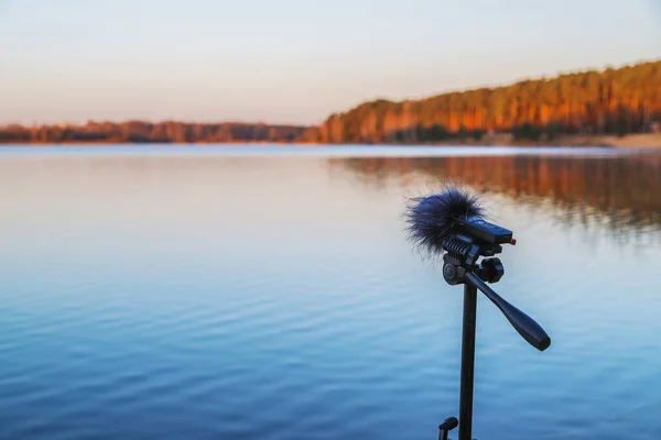 ポータブルレコーダーは湖畔の三脚に立っています 自然の音を録音する ストック写真