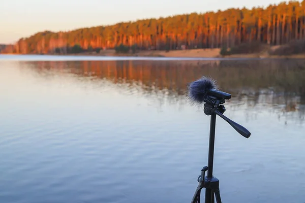 ポータブルレコーダーは湖畔の三脚に立っています 自然の音を録音する ロイヤリティフリーのストック画像