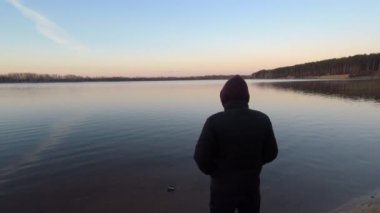 Sabahleyin adam gölün kıyısında duruyor. Doğa kavramıyla birlik