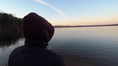 Sabahleyin adam gölün kıyısında duruyor. Doğa kavramıyla birlik