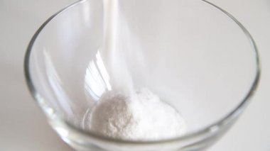 Beyaz arka planda cam bir kaseye pirinç unu döküyorum. Hamur hazırlığı. 